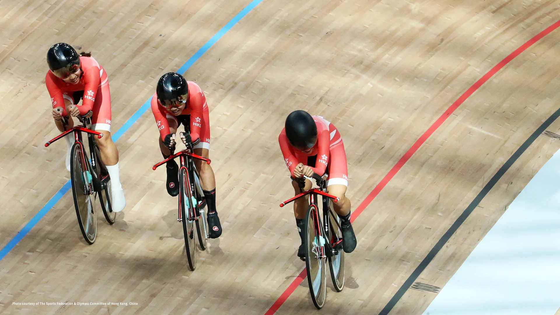 Three women cyclists wearing Hong Kong lycra racing on bicycles.